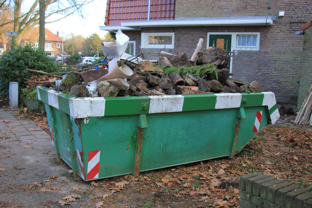 Ipswich waste service's green skip bin with hazard strips on the corners filled with tree waste