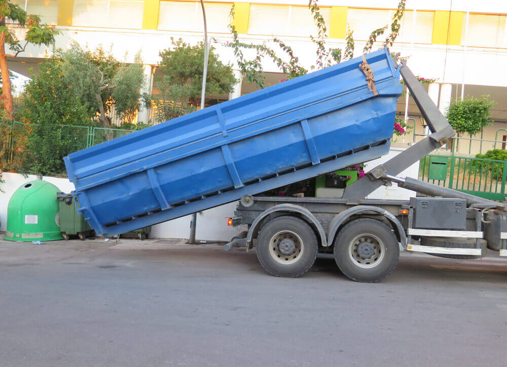 image of skip bin hire Ipswich's truck unloading a large blue bin onto the road
